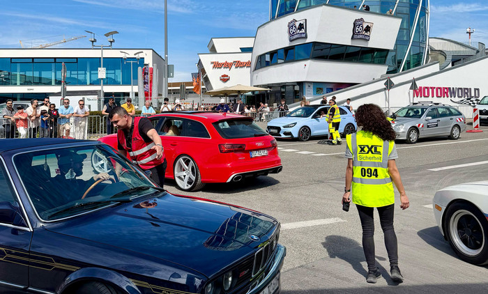 XXL-Sicherheitsmitarbeiter sichern eine Fahrzeugveranstaltung auf dem Gelände der Motorworld und koordinieren den Fahrzeugverkehr